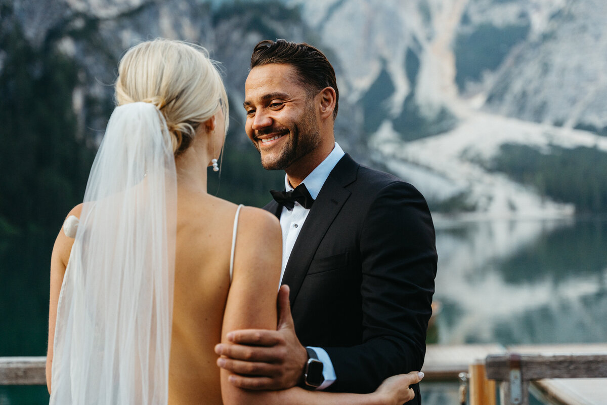Bride and groom holding hands on wooden dock with mountain backdrop