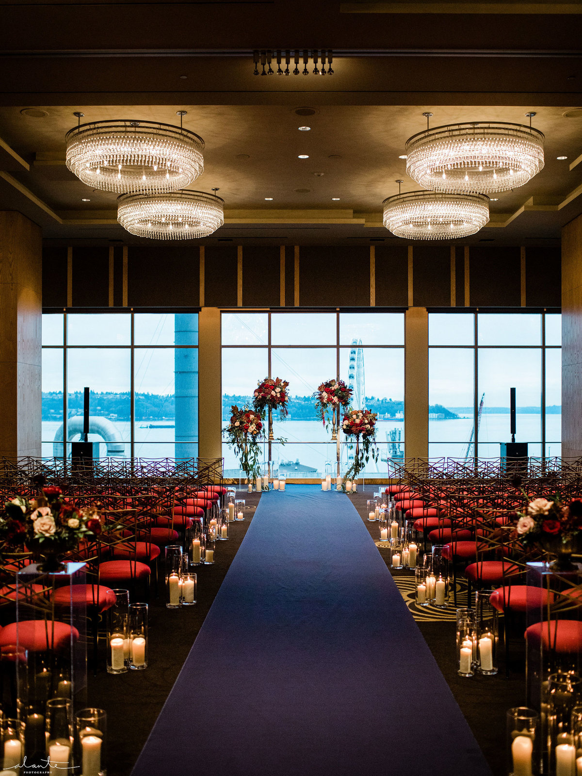 Winter wedding aisle at the Four Seasons Hotel in Seattle with navy blue aisle runner, cermony flowers, and aisle candles