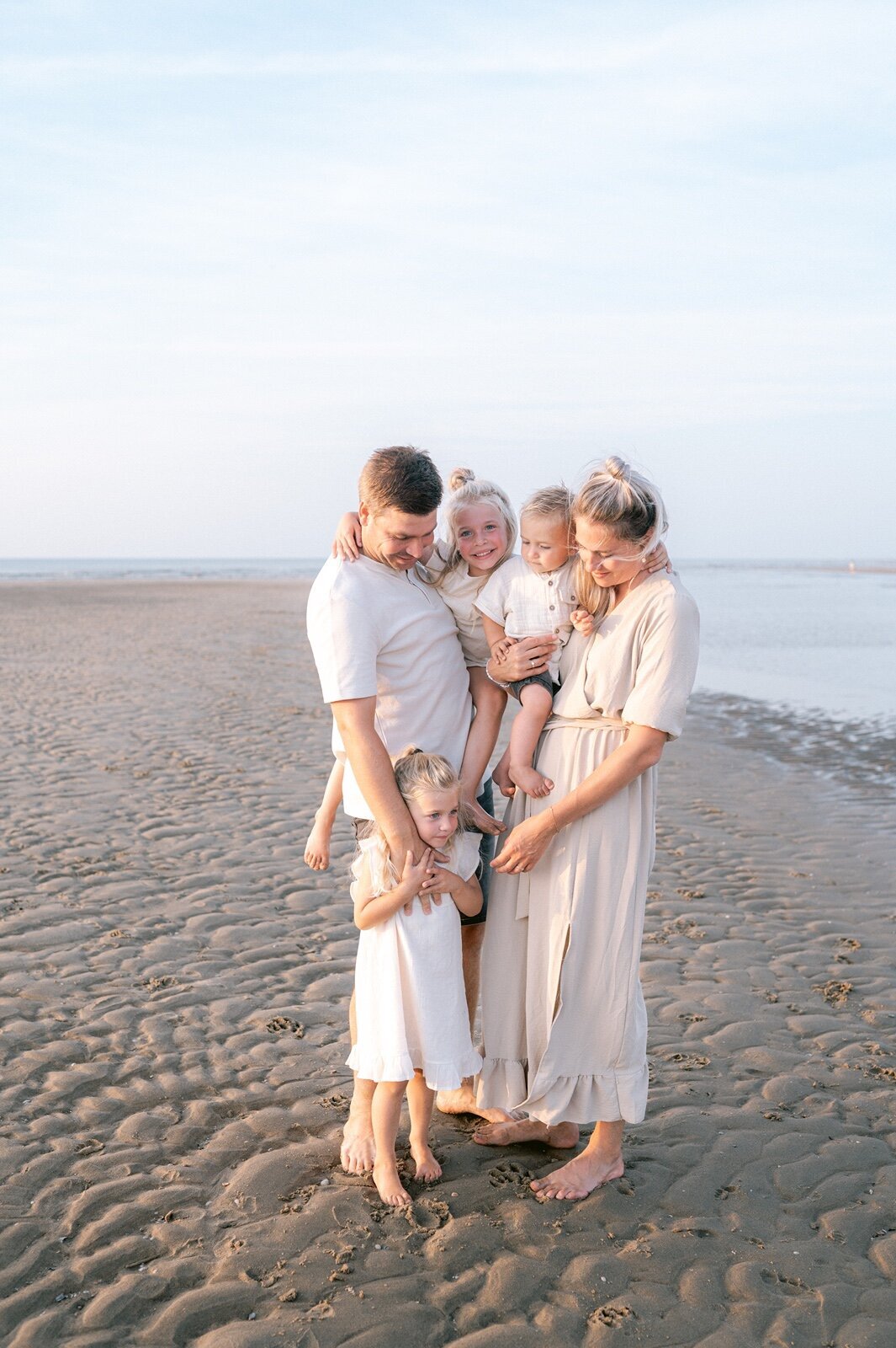 Gezin staat op het strand en kijkt naar elkaar