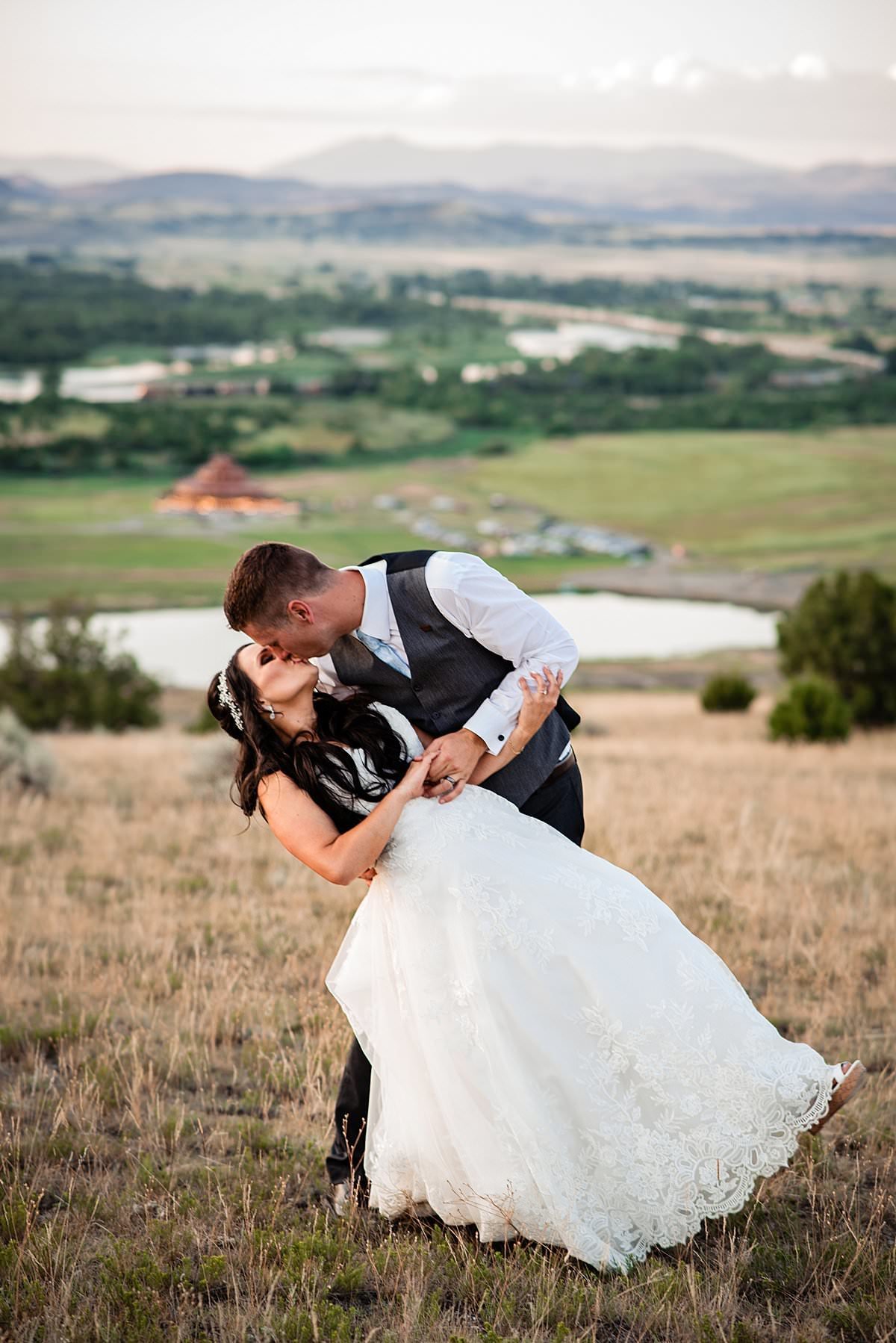 Groom dipping his wife on the mountain top overlooking Headwaters Ranch in the valley below
