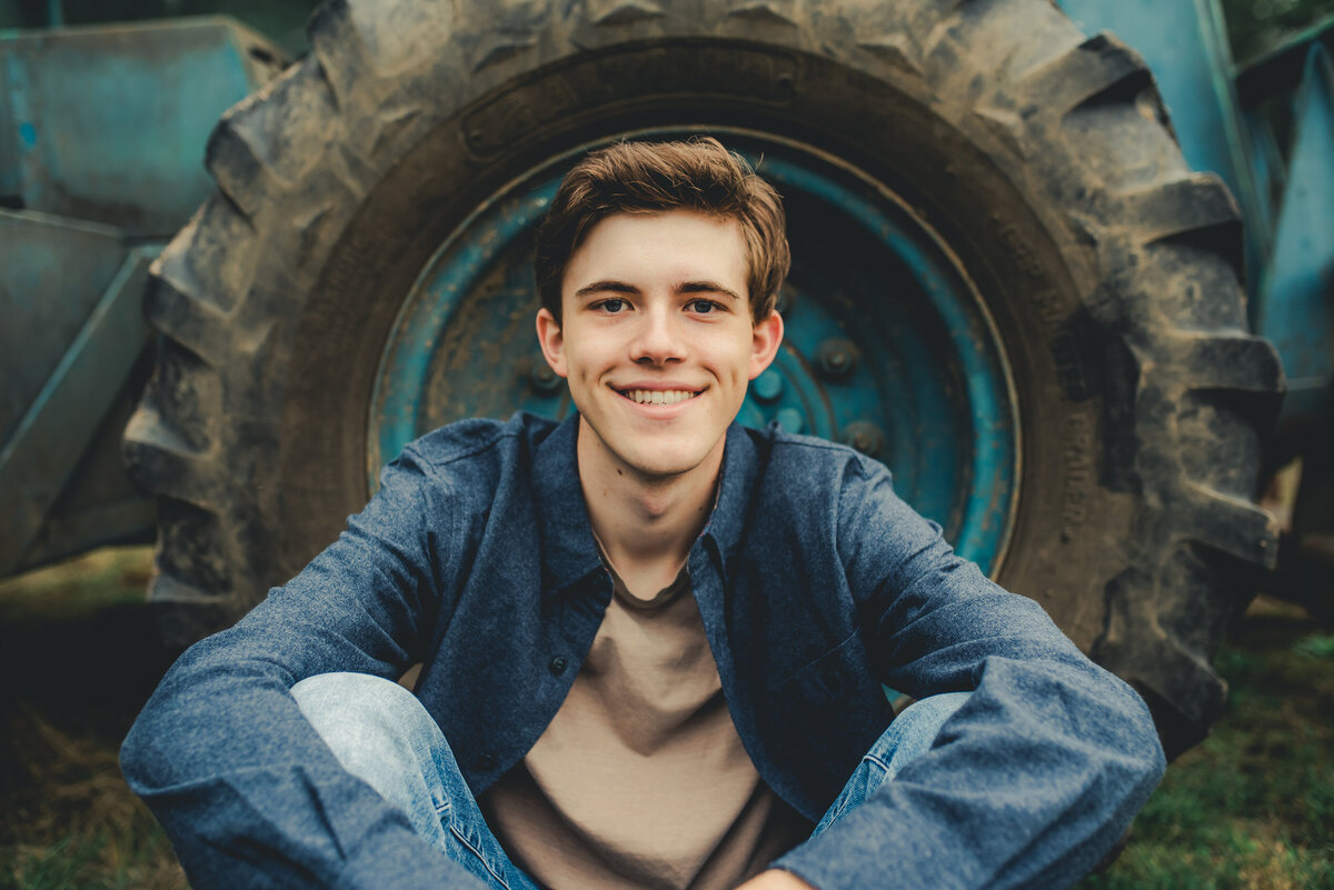 senior boy sitting by tractor