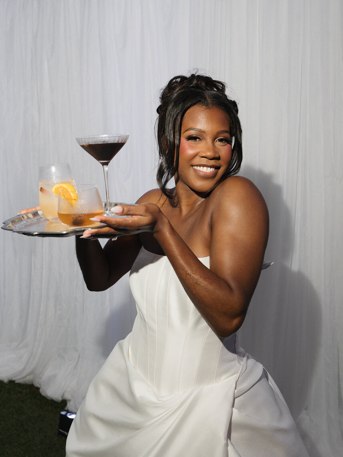 A bride carrying a tray of cocktails