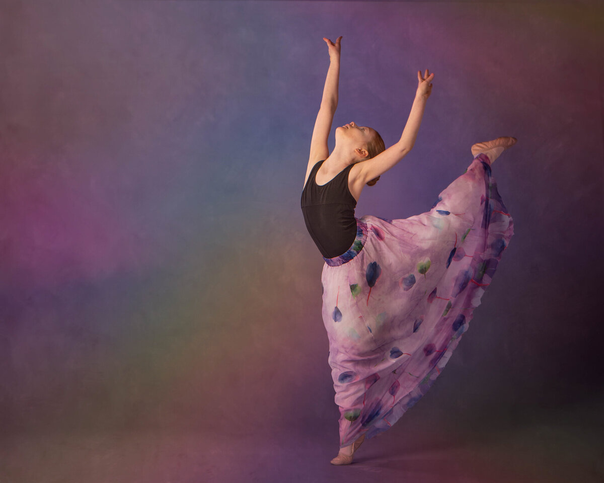 Artistic studio portrait of a young ballerina in a flowing gown performing a graceful leap. Captured in Overland Park, Kansas, this creative setup is ideal for families seeking elegant and refined child photography