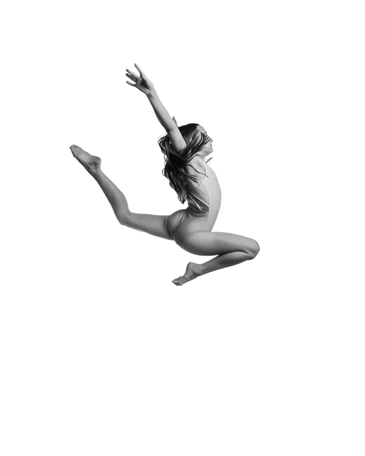 Black and white gymnastics portrait of a gymnast in a stag leap on a white backdrop by las vegas gymnastics photographer