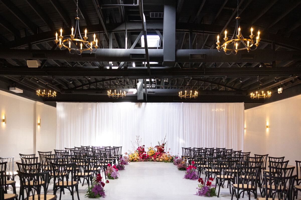 up to 200 guests in Locus for ceremony with draped backdrop and statement ground floral arch piece