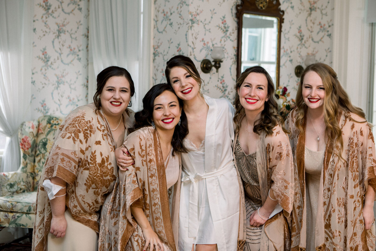 bride with bridesmaids in robes for New Years Eve wedding at the Lyman Estate in Waltham Massachusetts.