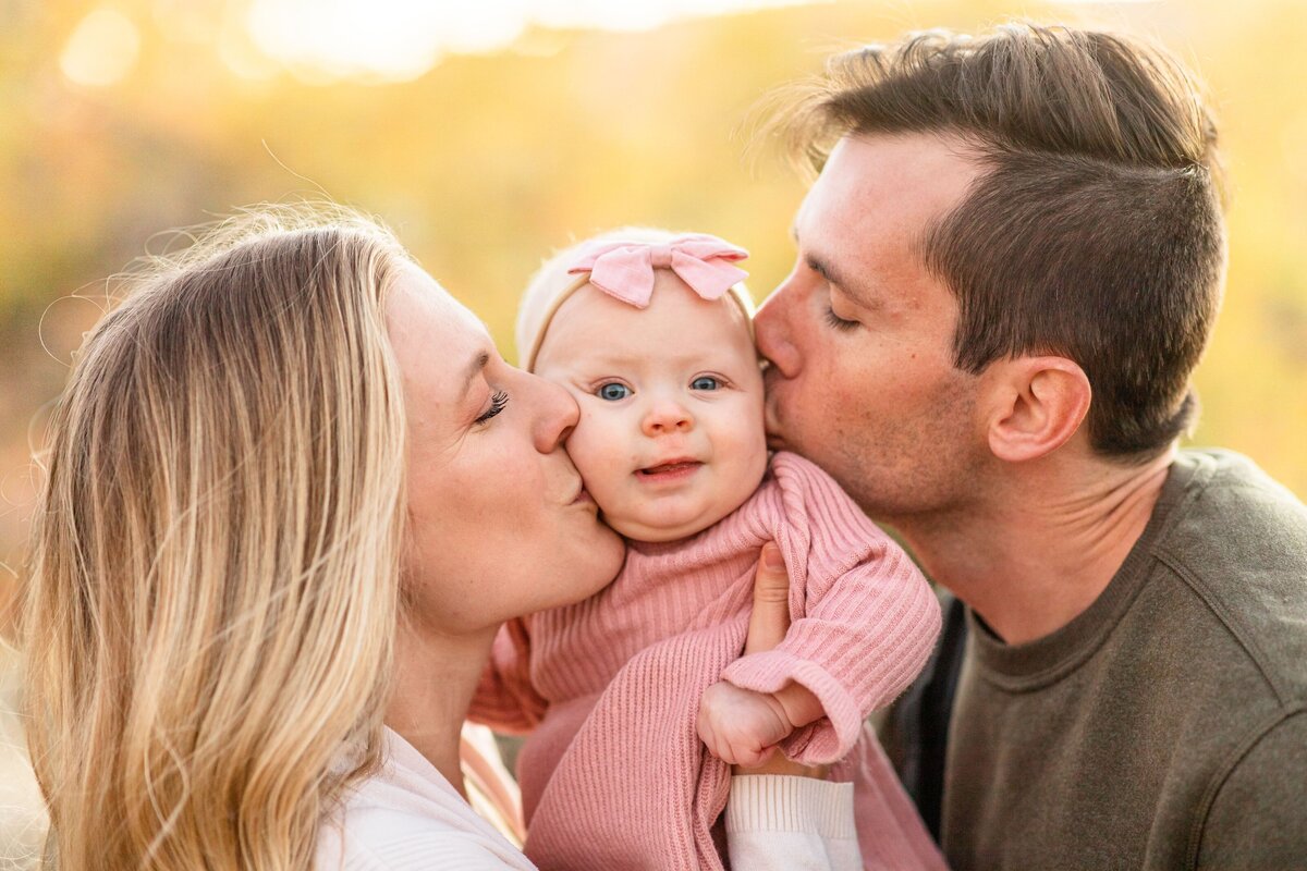 parents kissing their baby on the cheek