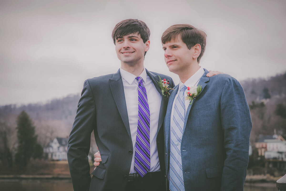 LGBTQ couple look at view during winter wedding.
