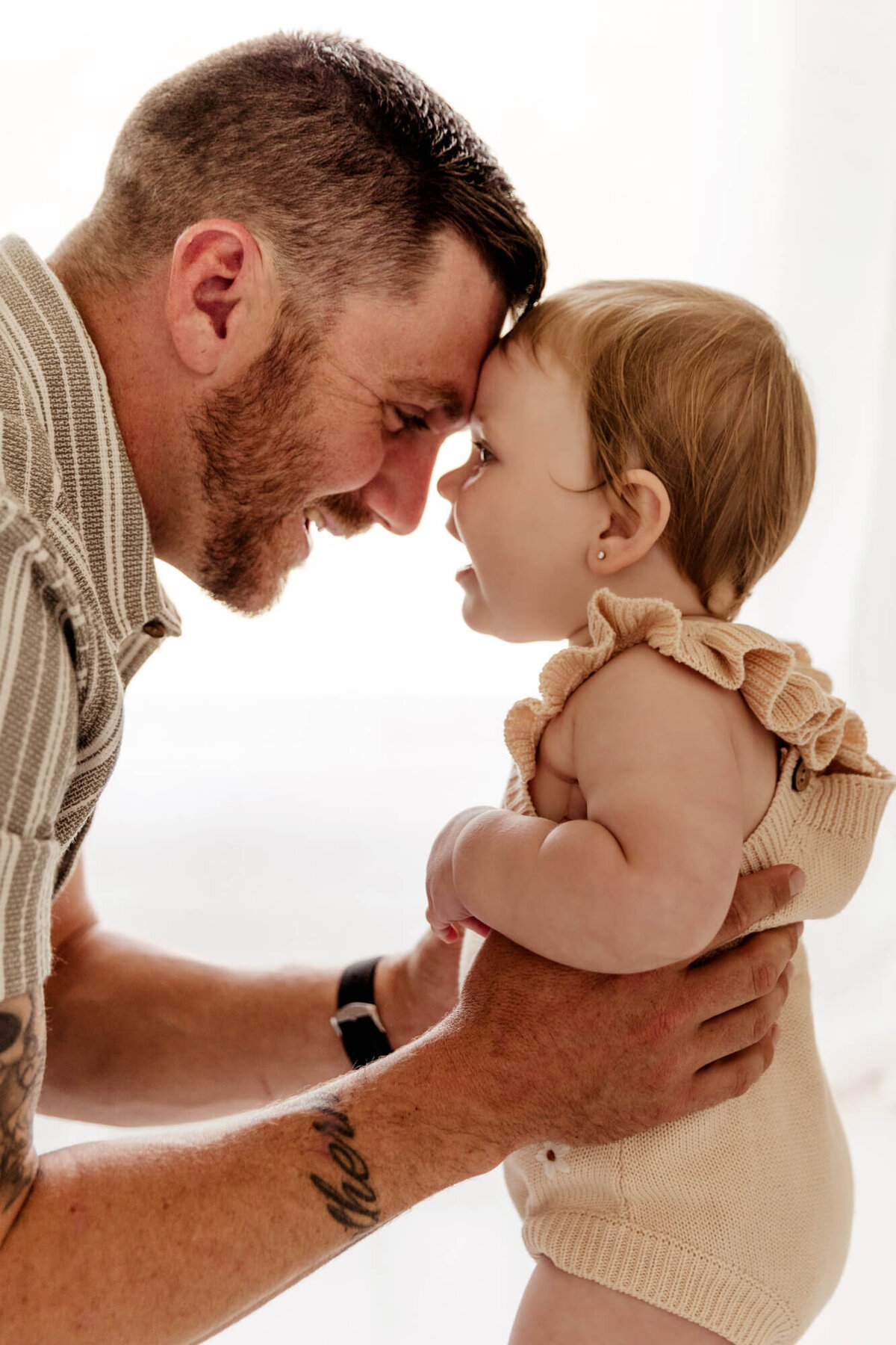 One year old girl touches her forehead to her father's head during a one year old photo session in Yukon, Oklahoma.