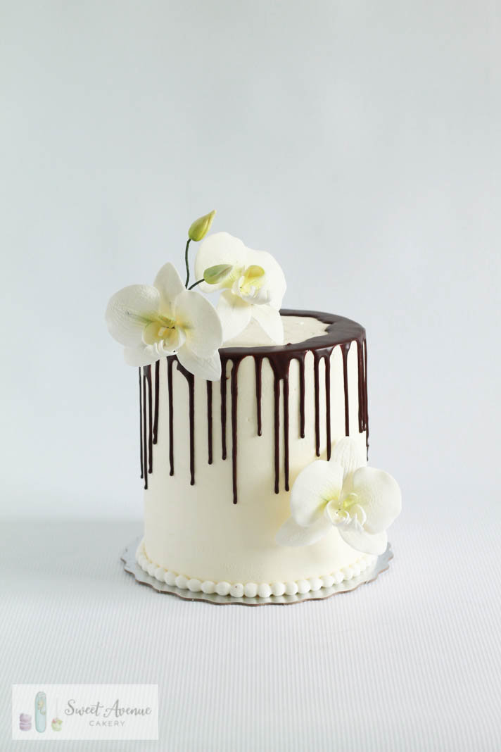 single tier white buttercream chocolate drip cake with orchids