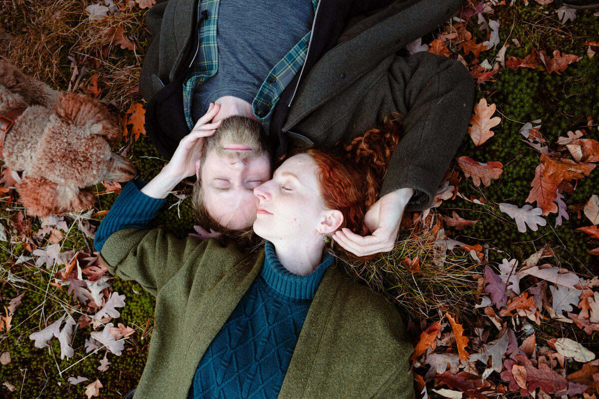 engaged-couple-lying-in-the-moss-and-fall-leaves-at-little-mellon-lake-ontario-1