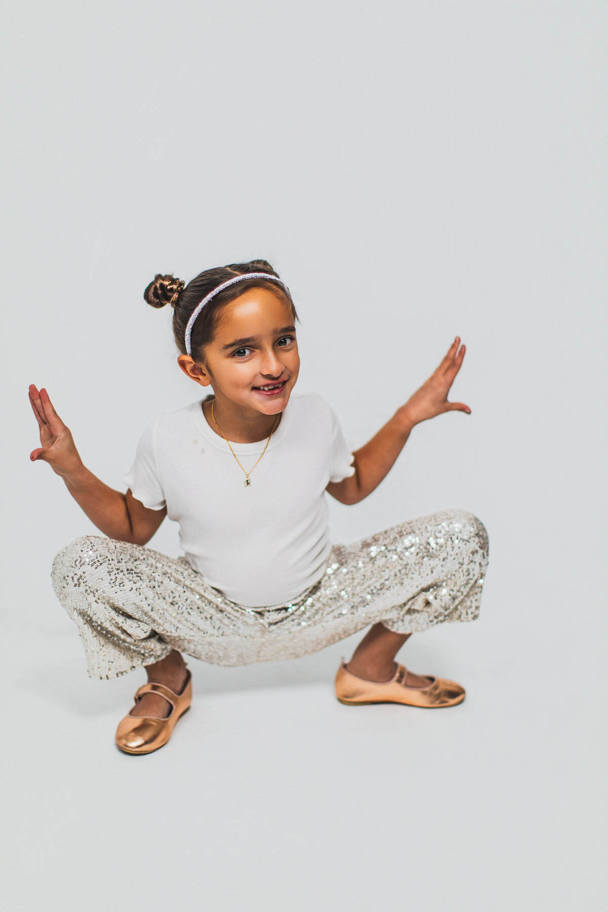 Dark skin girl with sparkly pants and cute hair poses for children's portraits in the Pittsburgh photography studio