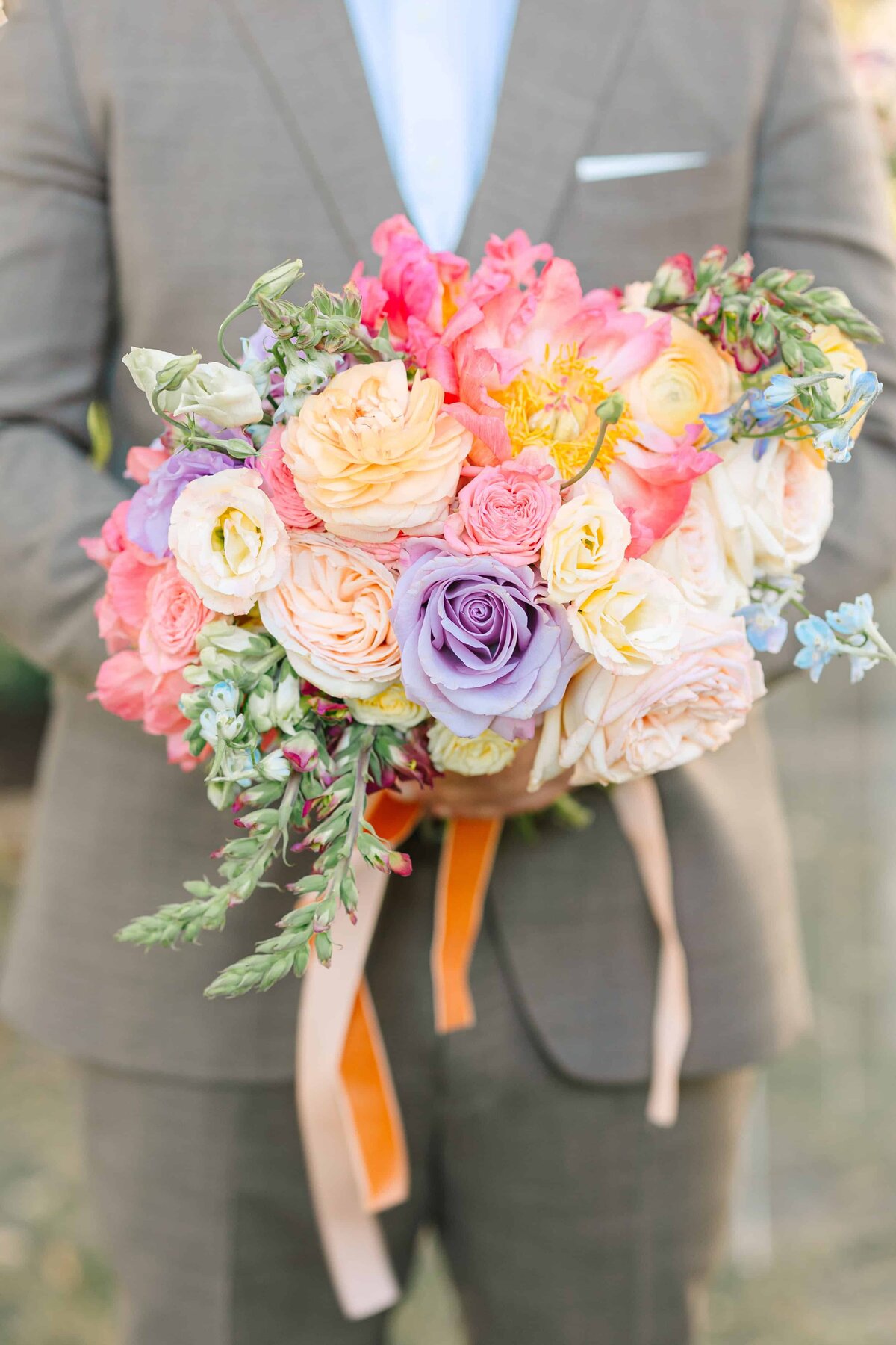 Groom holding a bright, vibrant wedding bouquet at a fresno wedding 