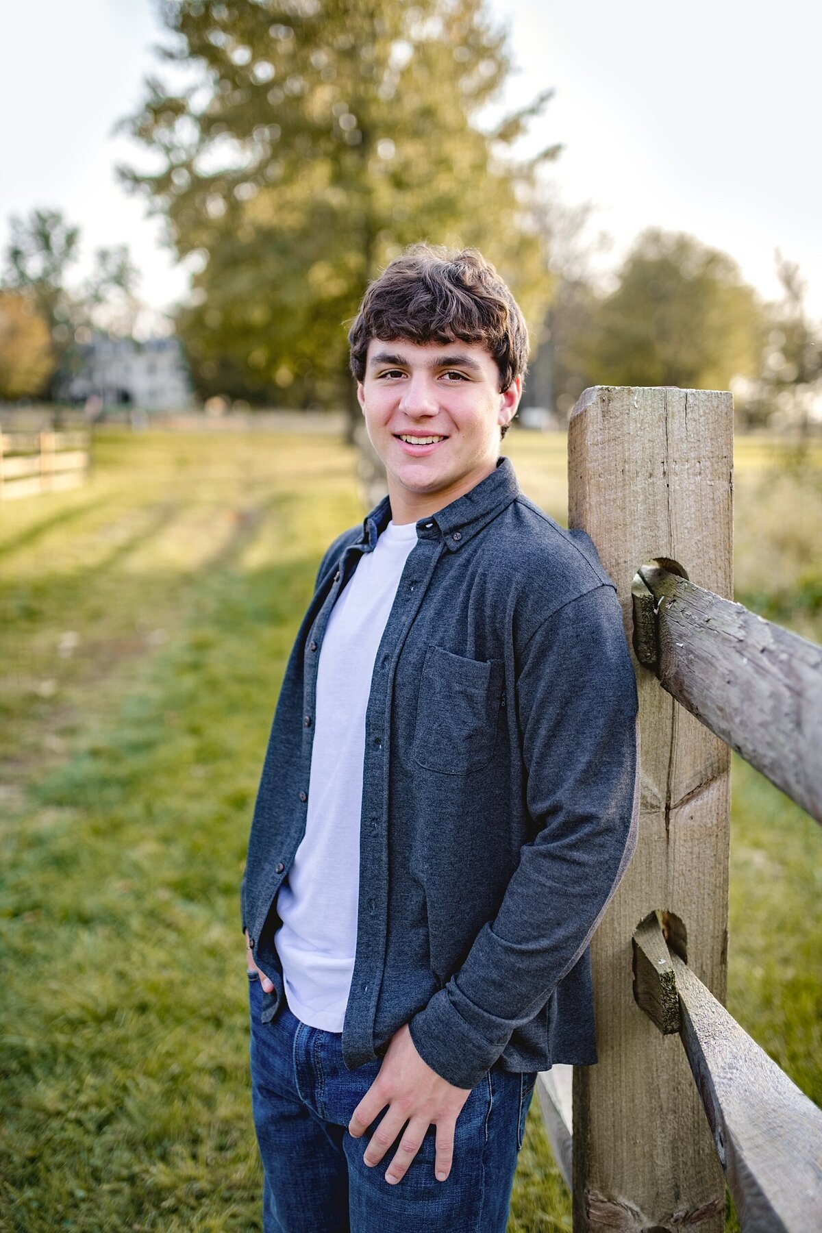 senior-guy-leaning-on-fence-in-fall