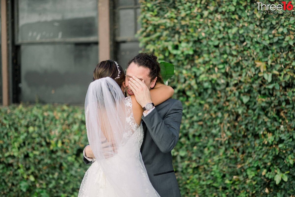 Groom wipes away tears as his Bride embraces him during after ceremony photo session