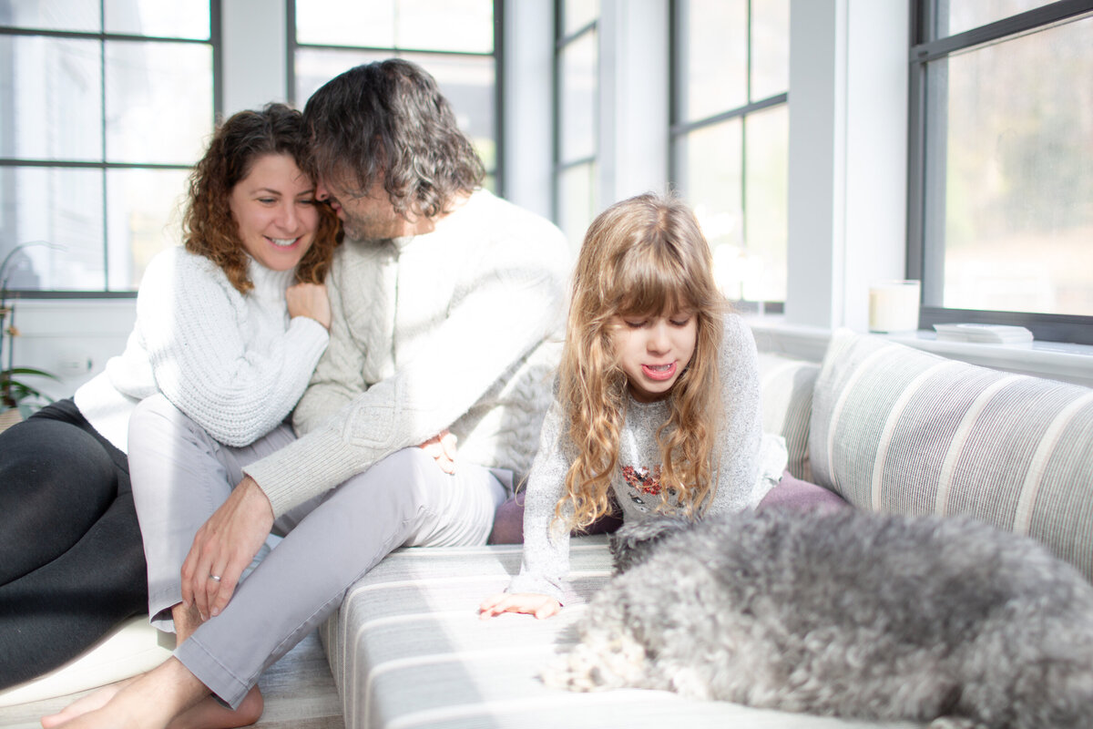 family of three in sunroom with dog