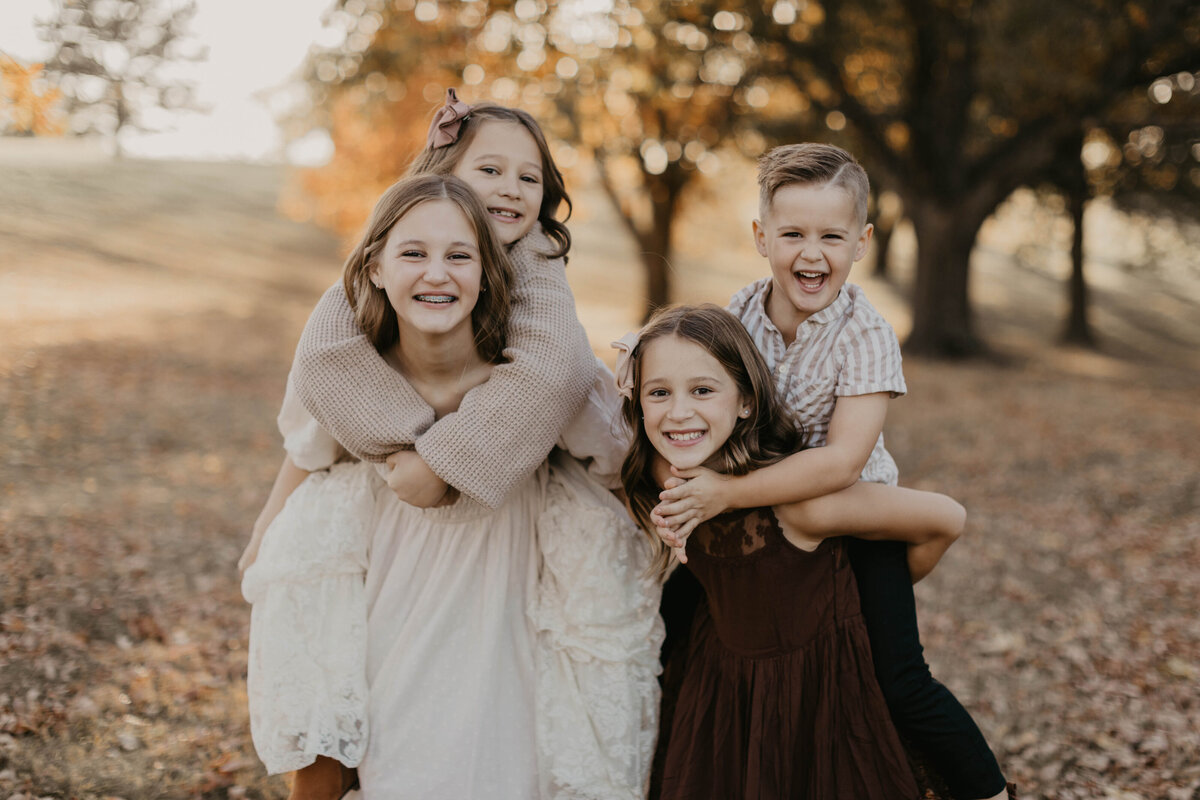 Siblings on each other doing piggy back rides. 