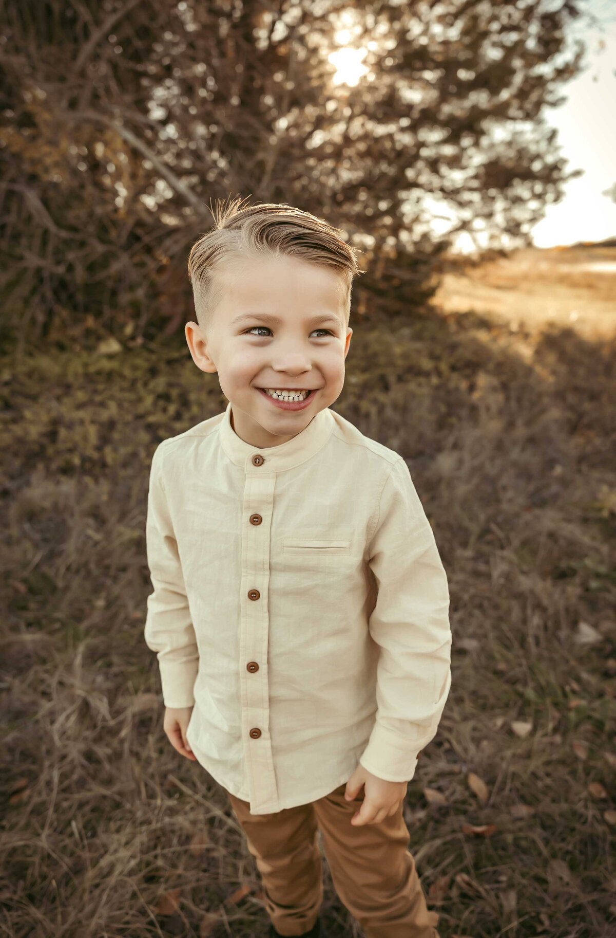 Boy smiling and wearing a light yellow shirt and a brown pants