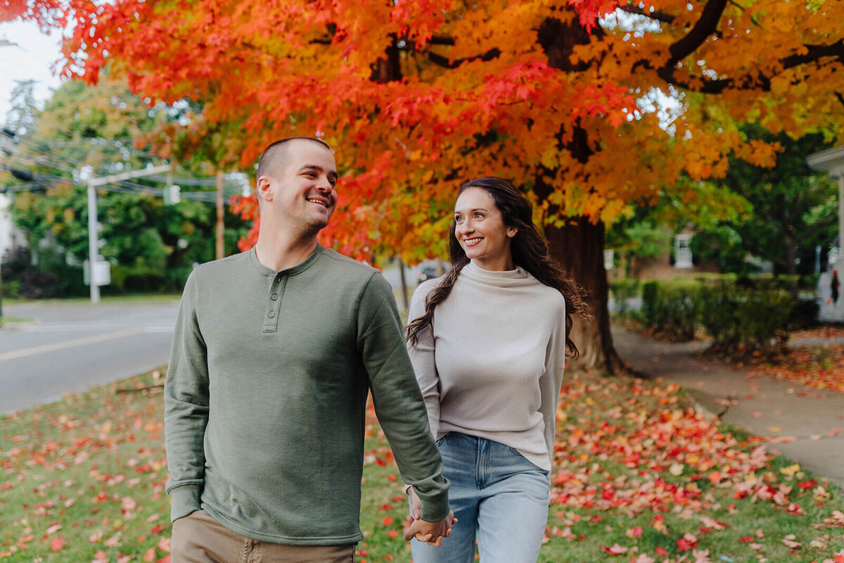 Couple walking along under a orange tree at Finger Lakes engagement session