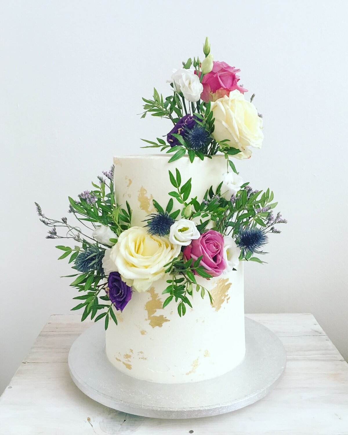 An elegant 2 tier wedding cake with flowers and specs of gold
