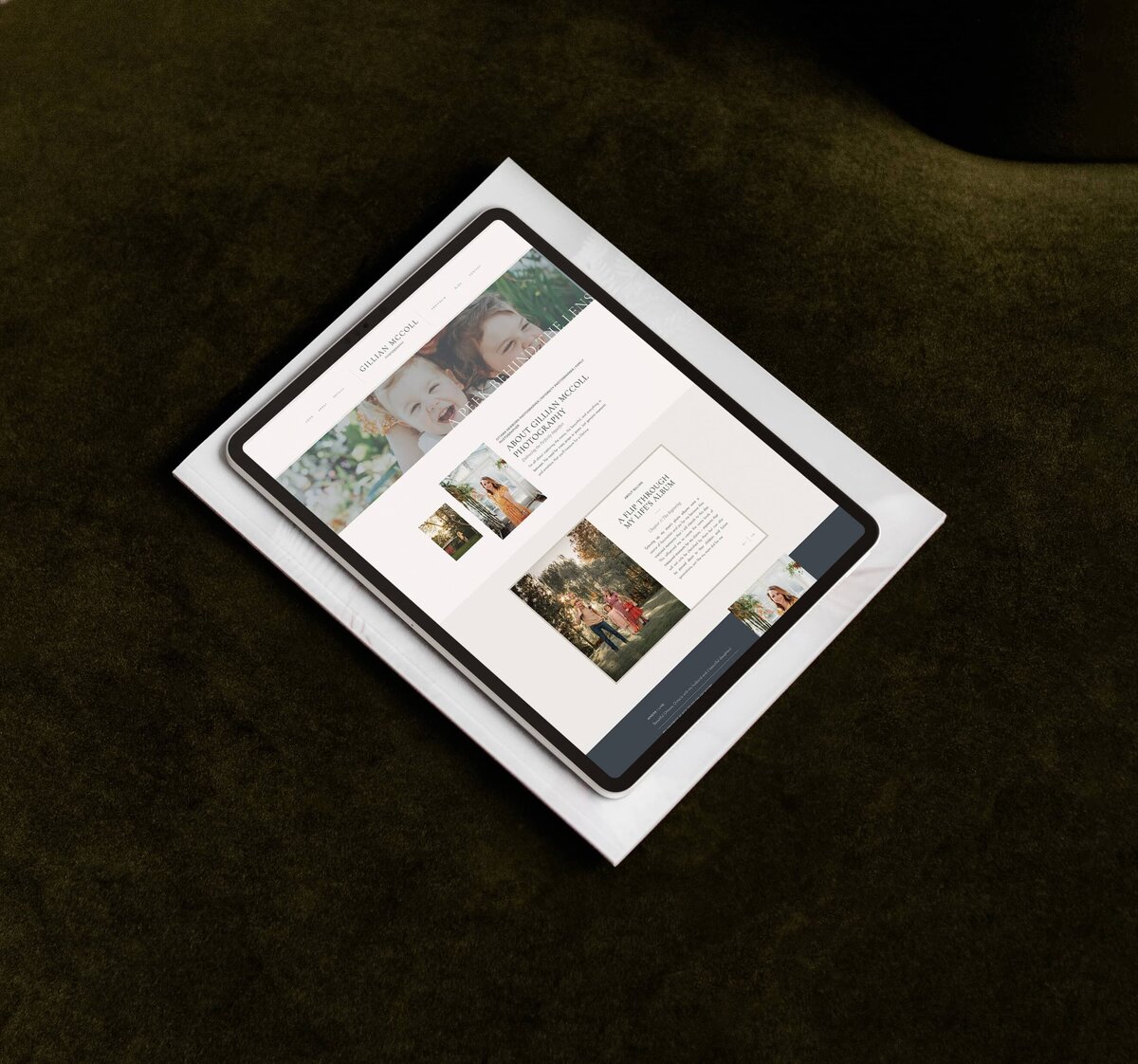 A tablet displaying a website with images of people and text rests on a white surface against a dark background, showcasing showit web design for luxury photographers.