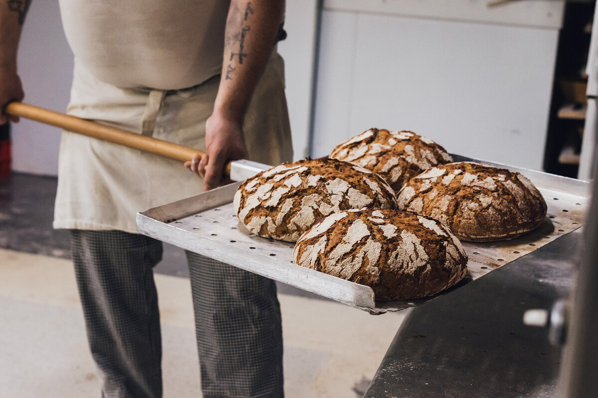 Bäcker nimmt frisch gebackenes Brot aus dem Ofen