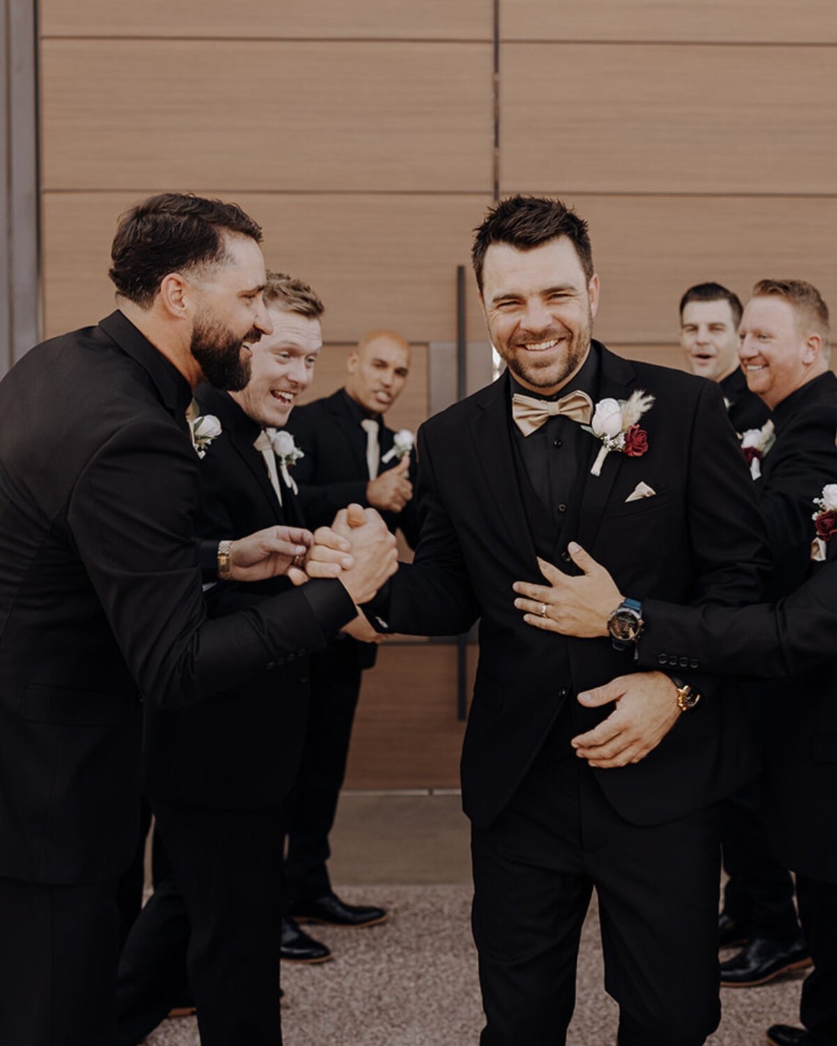 A groom and his guests dressed in black wedding suits