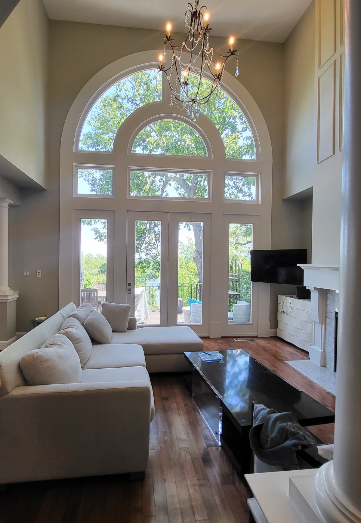 living room with large cream sofa and oversized coffee table wtih television popping out of the nook with cream bureaus