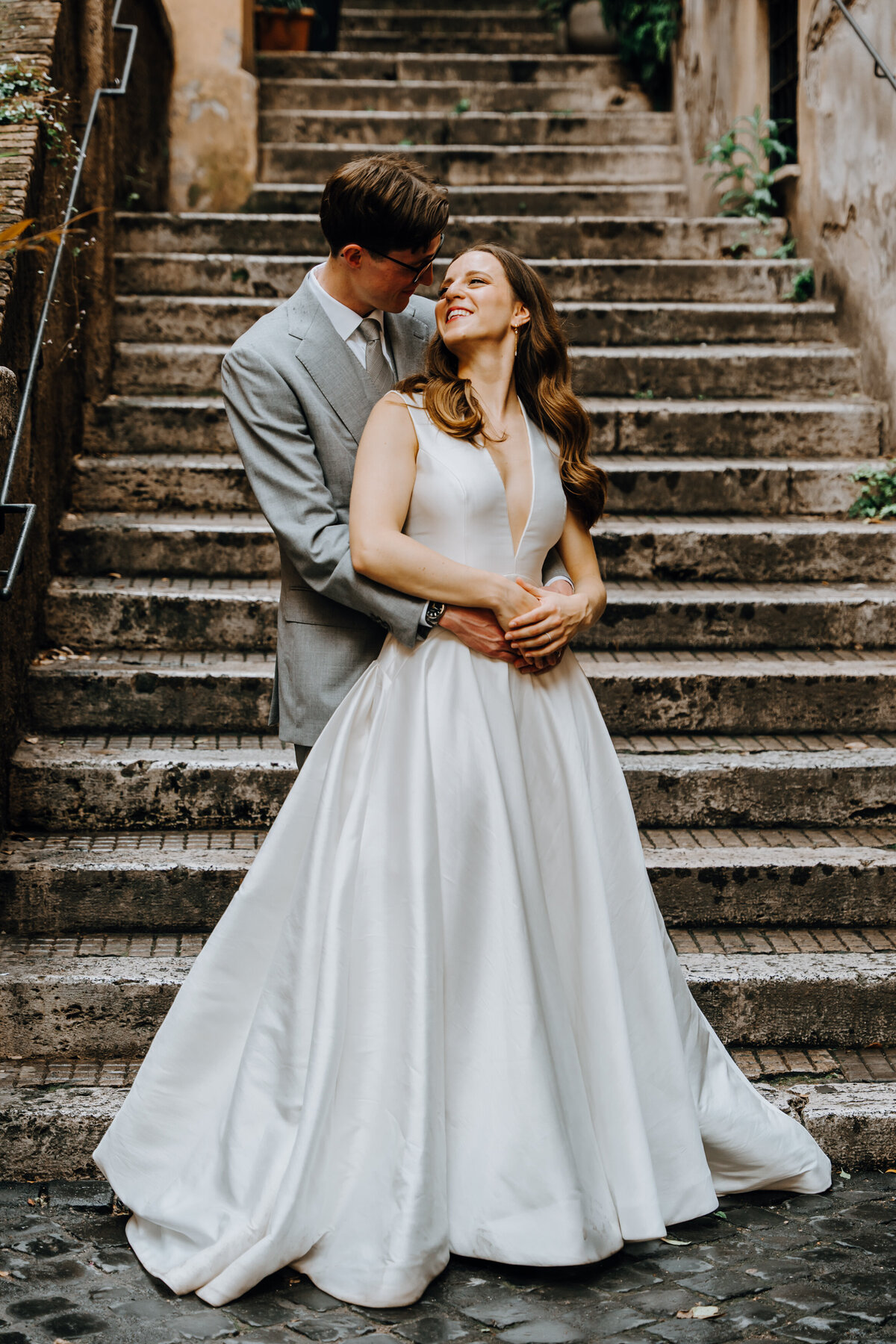 Couple standing on stone staircase in narrow Roman alley.