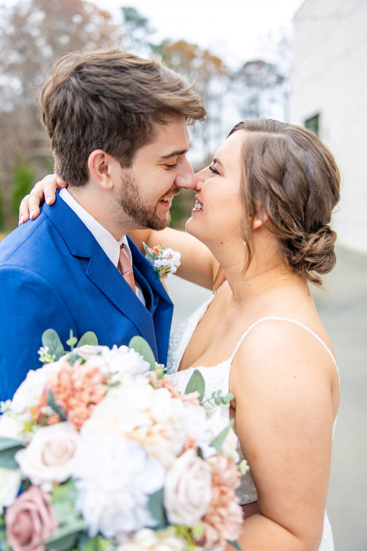 Bride and groom embracing while bride holds a bouquet of flowers