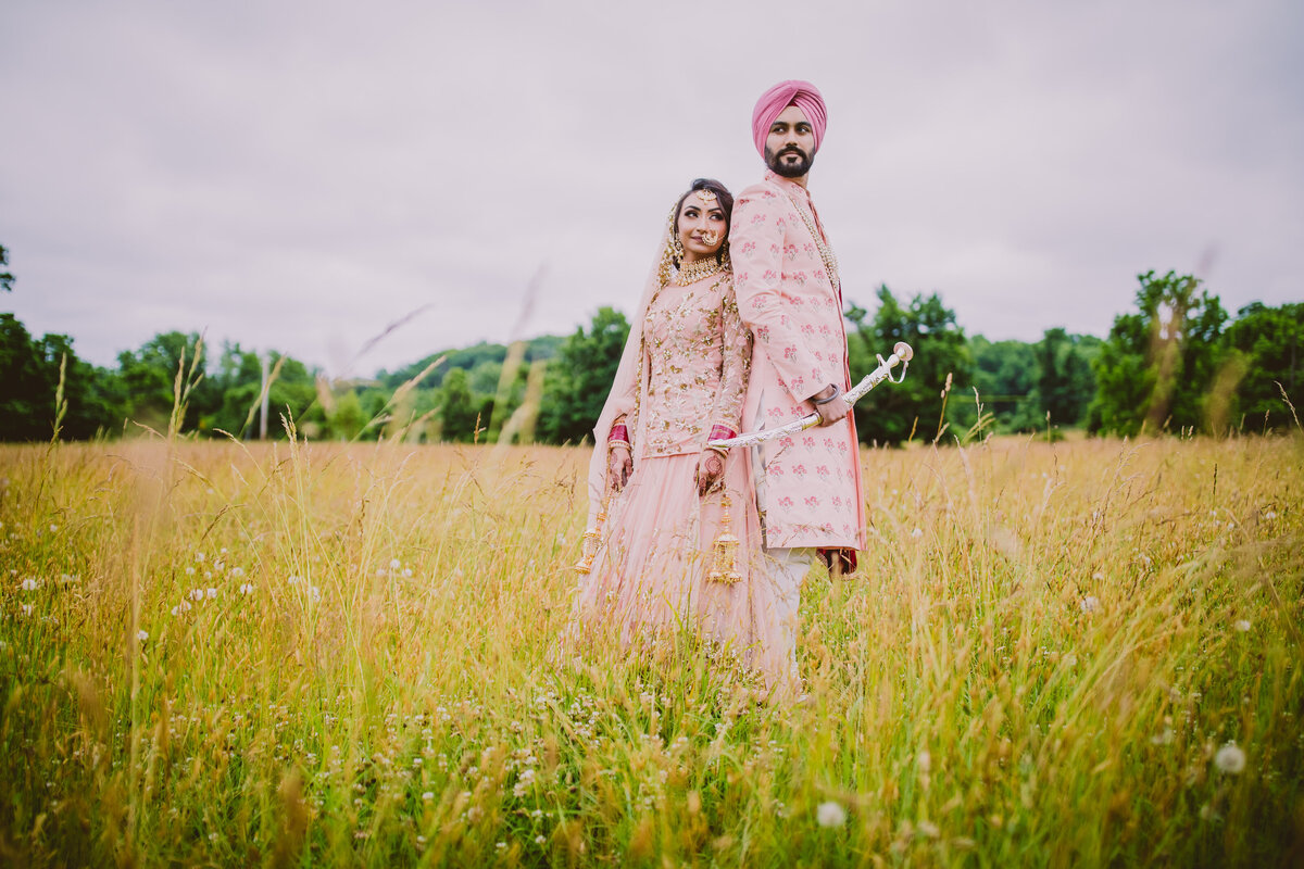 An indian sikh couple standing back to back in a field at a farm in new jersey after their anand karaj wedding ceremony