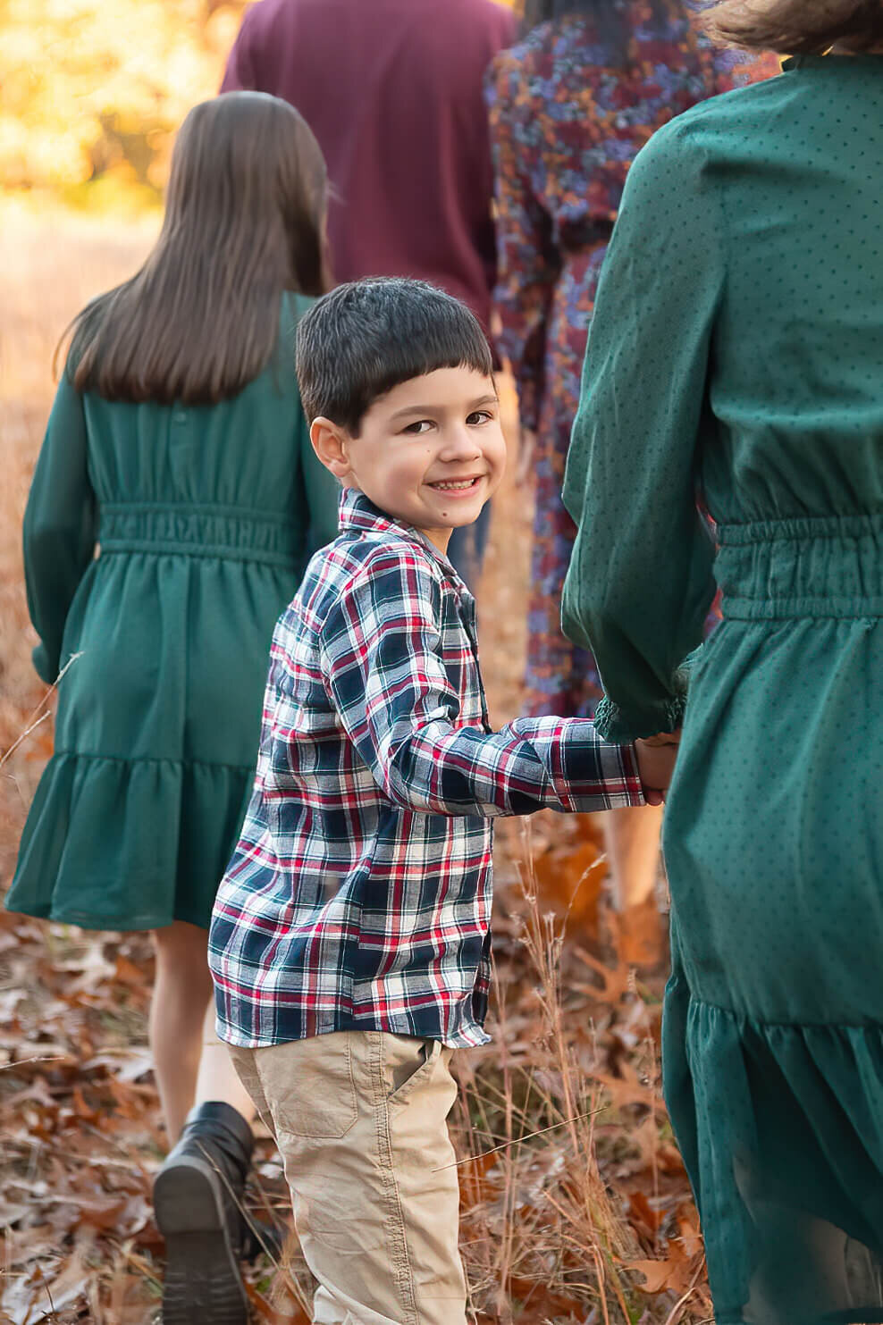 A young boy holds his sister's hand  and smiles as they walk across the grass on the Minute Man trail.
