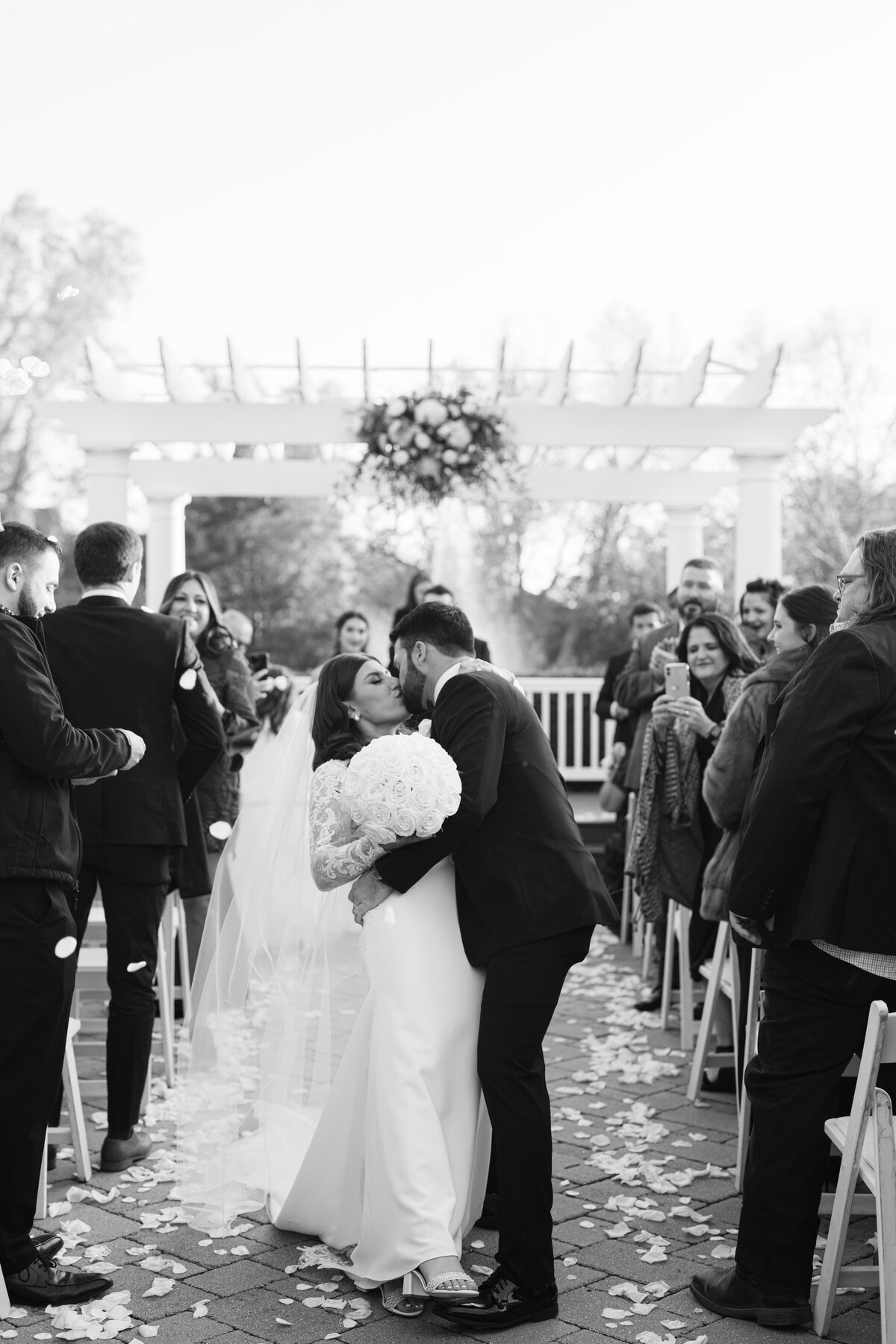Groom kisses his bride in the middle of the aisle just after saying I do by Lacey Graham photographer in Illinois
