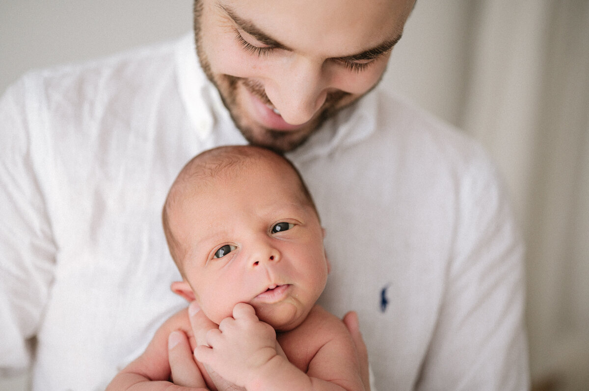 Father holds his newborn baby during a family photoshoot