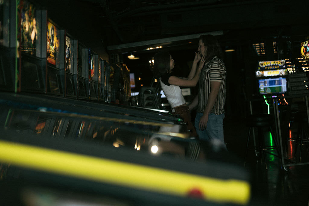 A person kissing their partner's hand in an arcade.