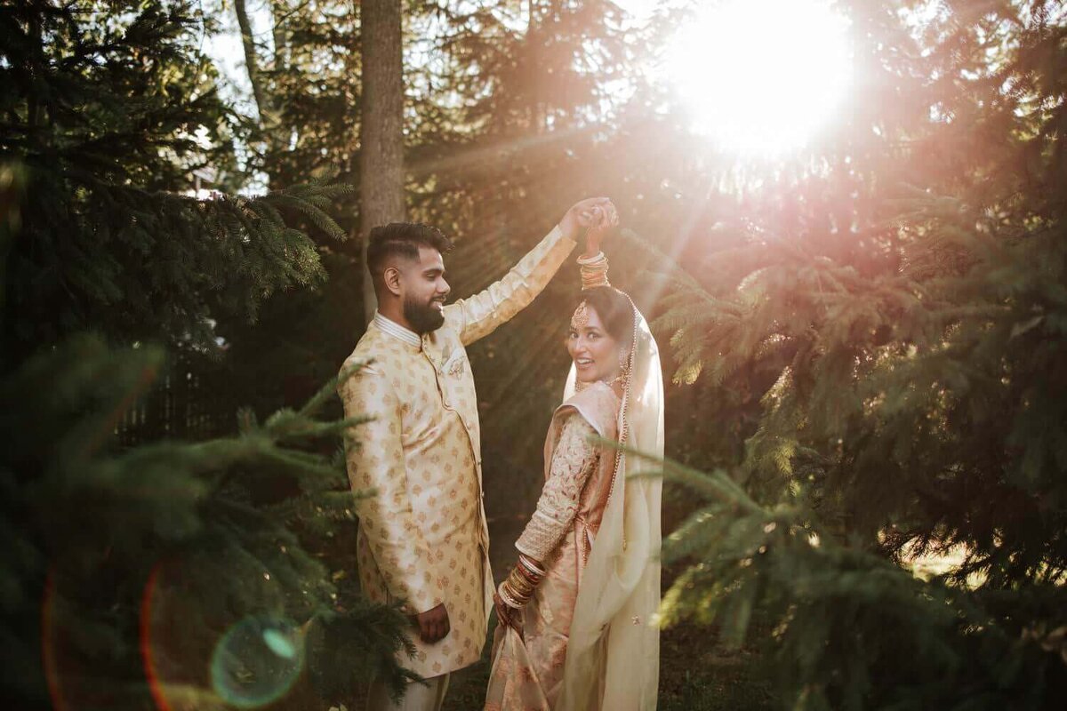 South Asian bride and groom embracing each other surrounded by greenery in Philadelphia as the sun sets.