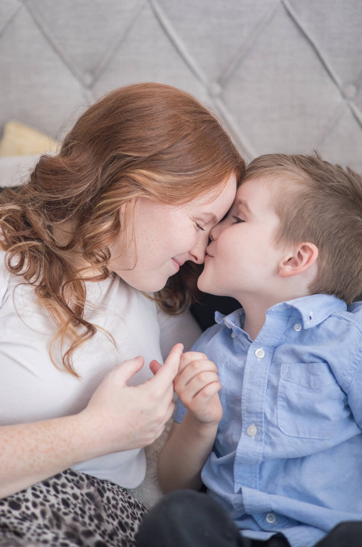 young boy wearing a blue shirt kissing his mom's nose