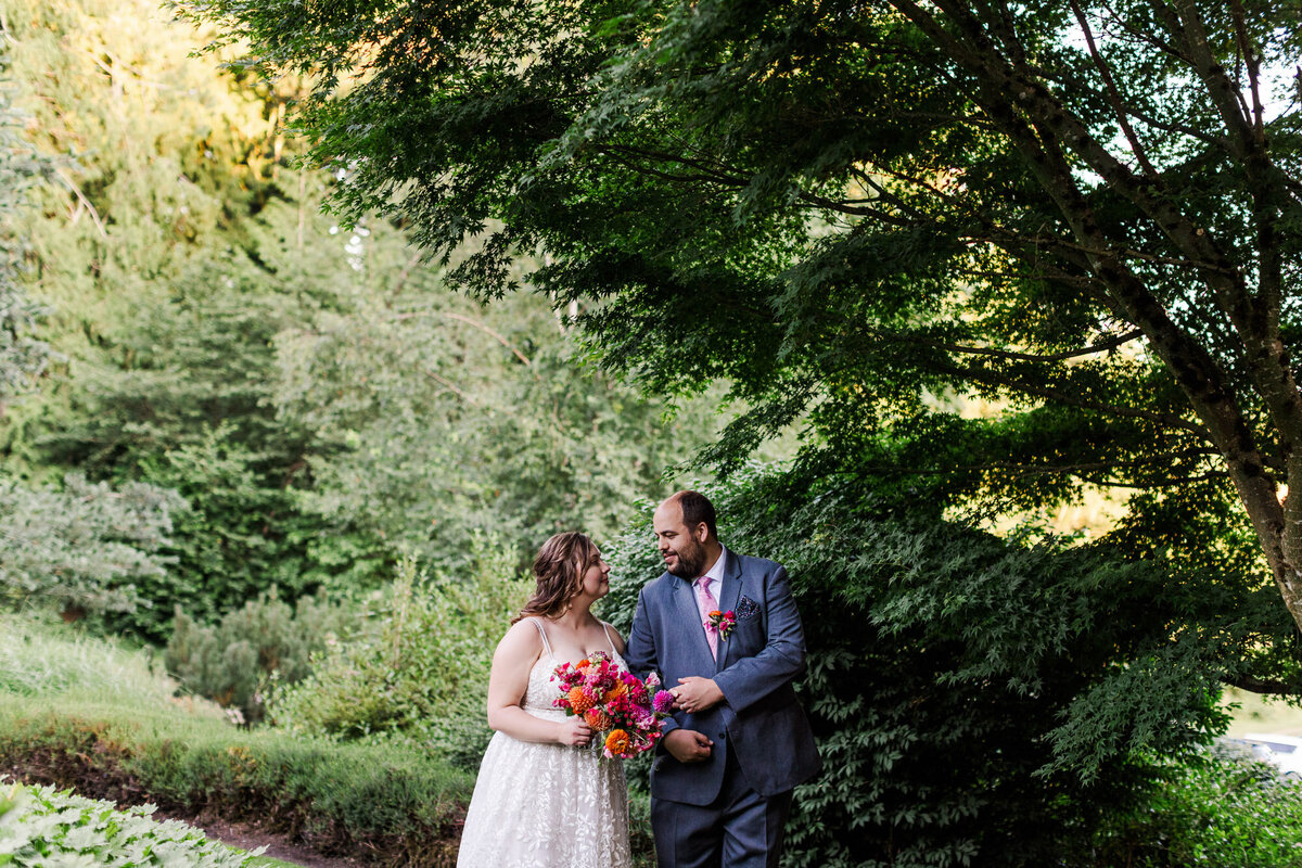 Bride-and-groom-walking-through-woodland-wonderland-paths-at-outdoor-venue-Twin-Willow-Gardens-in-Snohomish-WA-photo-by-Joanna-Monger-Photography