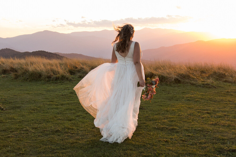 bride walks toward the sunset with epic mountain view at max patch in nc