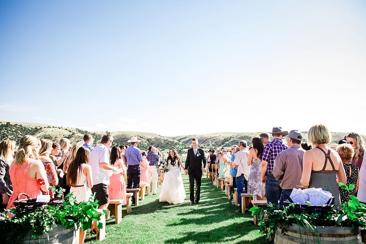 Newlywed couple walking back up the aisle during their outdoor ceremony recessional