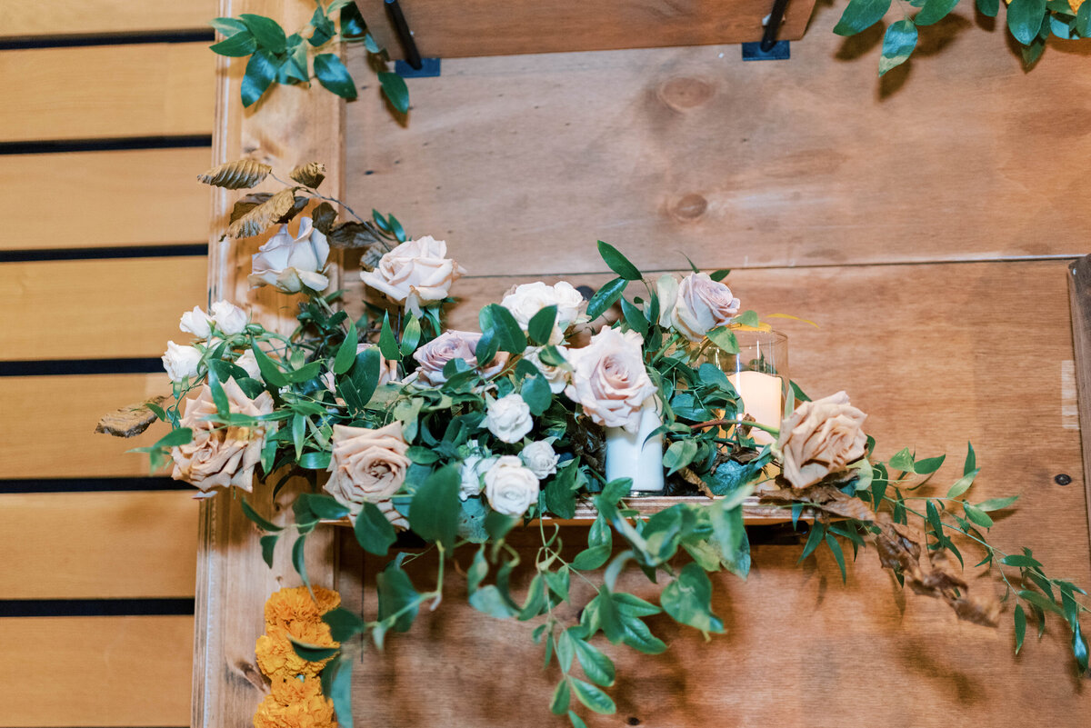Florals and greenery decorating a wooden wedding reception backdrop