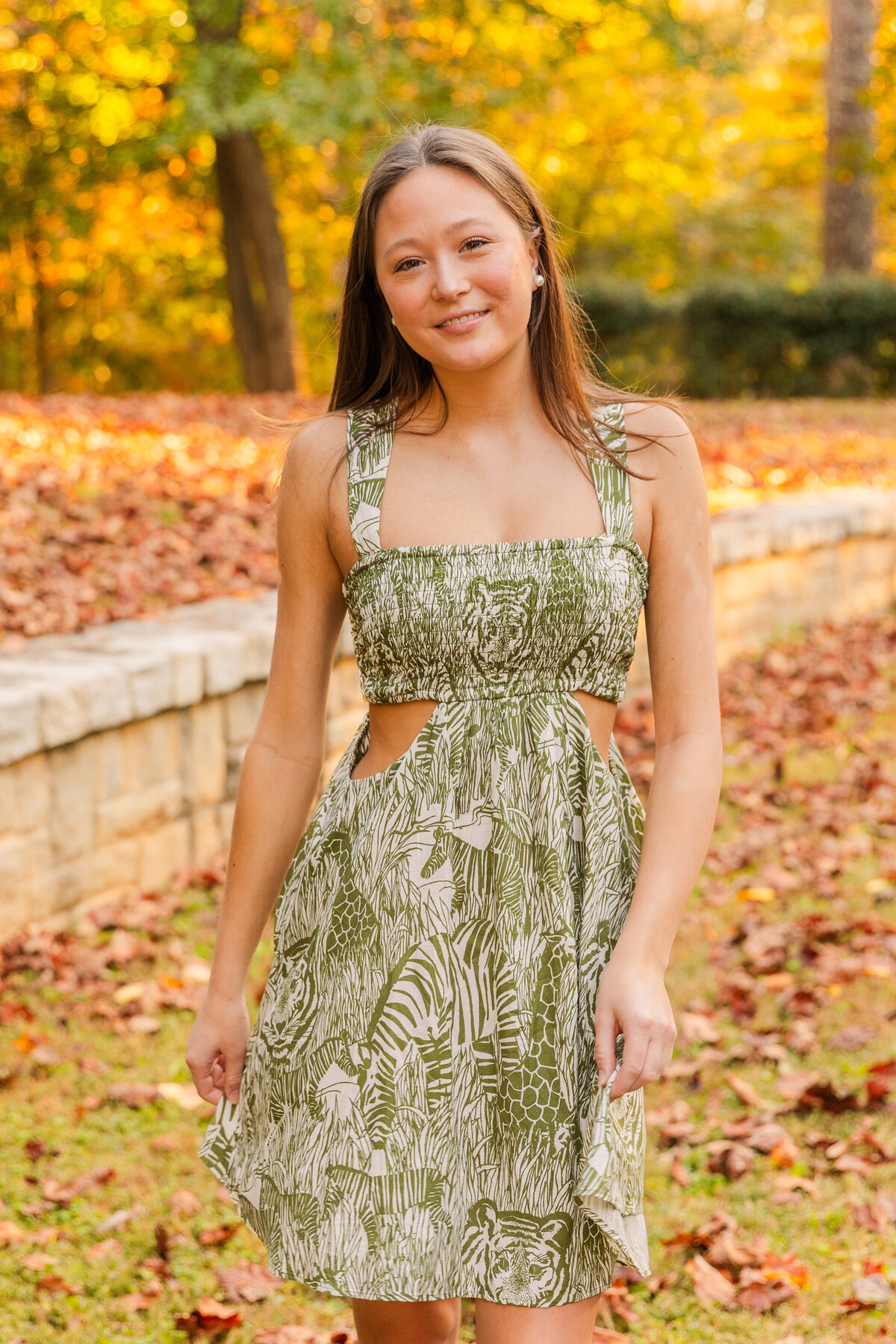 senior girl walking in a Buckhead Atlanta park wearing a green and white dress during photo session