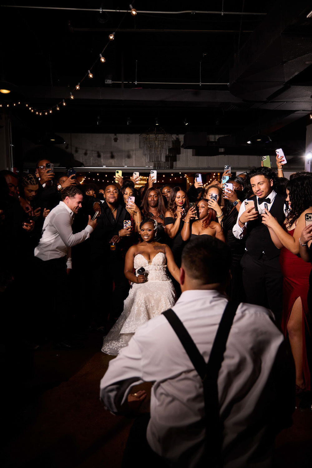 Bride and groom dancing while guests taking a photo of them