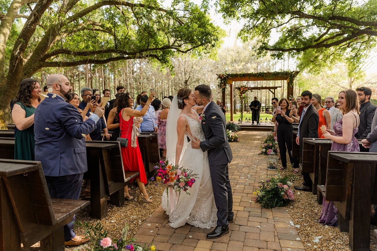 Groom Kissing Bride during exit from wedding ceremony at Club Lake Plantation Apopka Florida