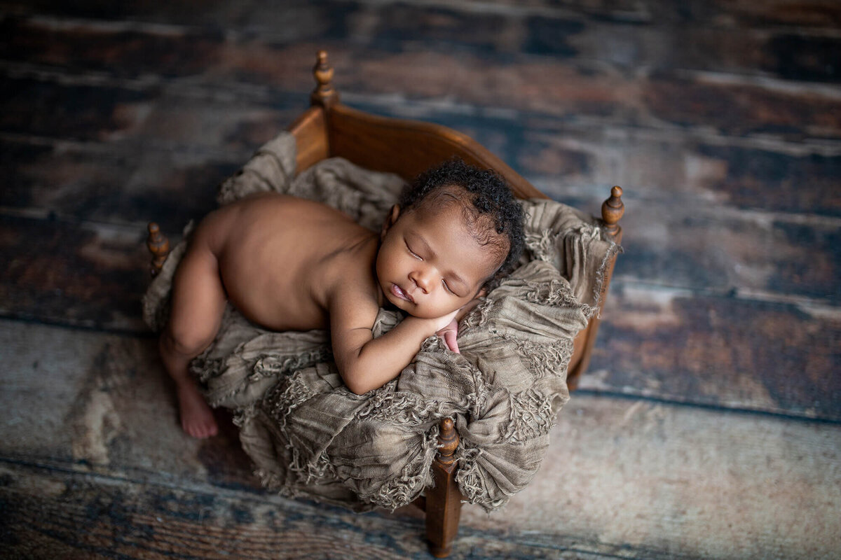 Rustic naked newborn pose with little boy on a wood daybed and barnwood flooring. Located at studio in Riverview FL with Sarah Wyndham Photography