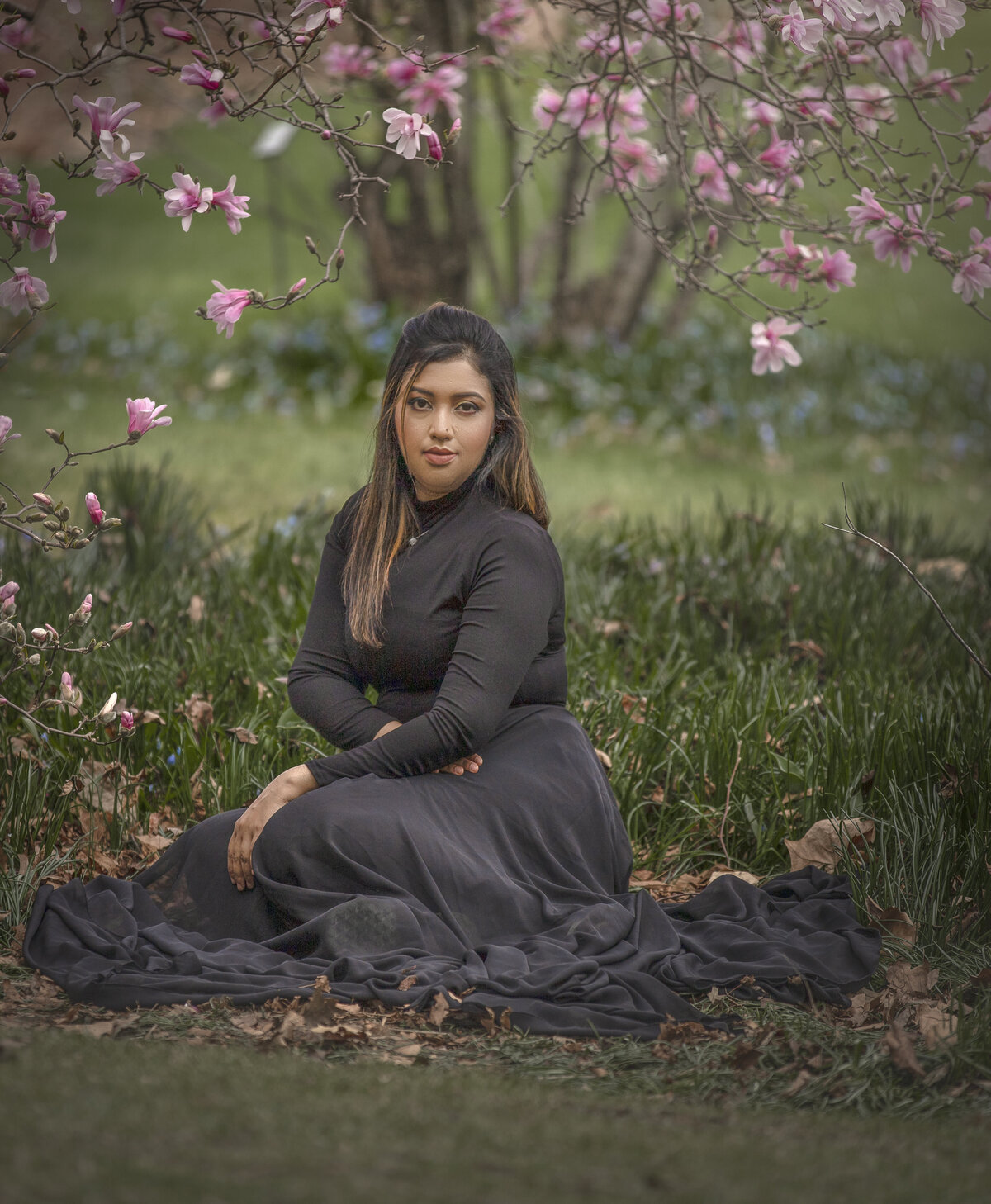 Ottawa Ontario photograher takes  photo of young lady in the magnolias wearing a black dress during outdoor photo session in ottawa Ontario