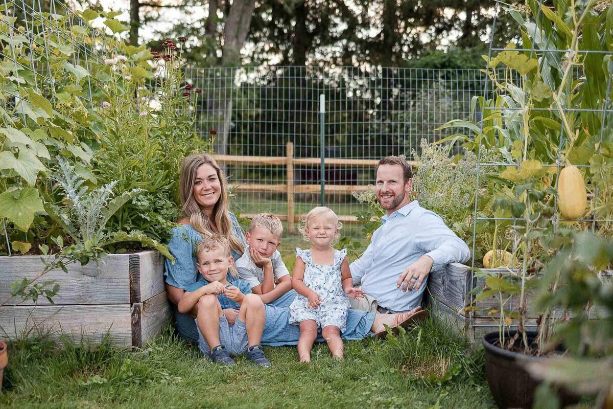 Large family sitting in garden during backyard family photography session.
