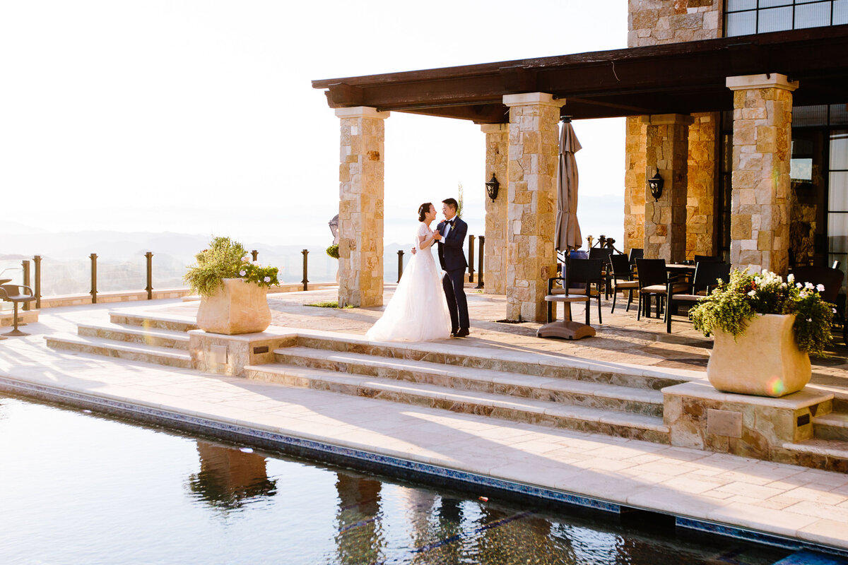 bride and groom dance next to a pool