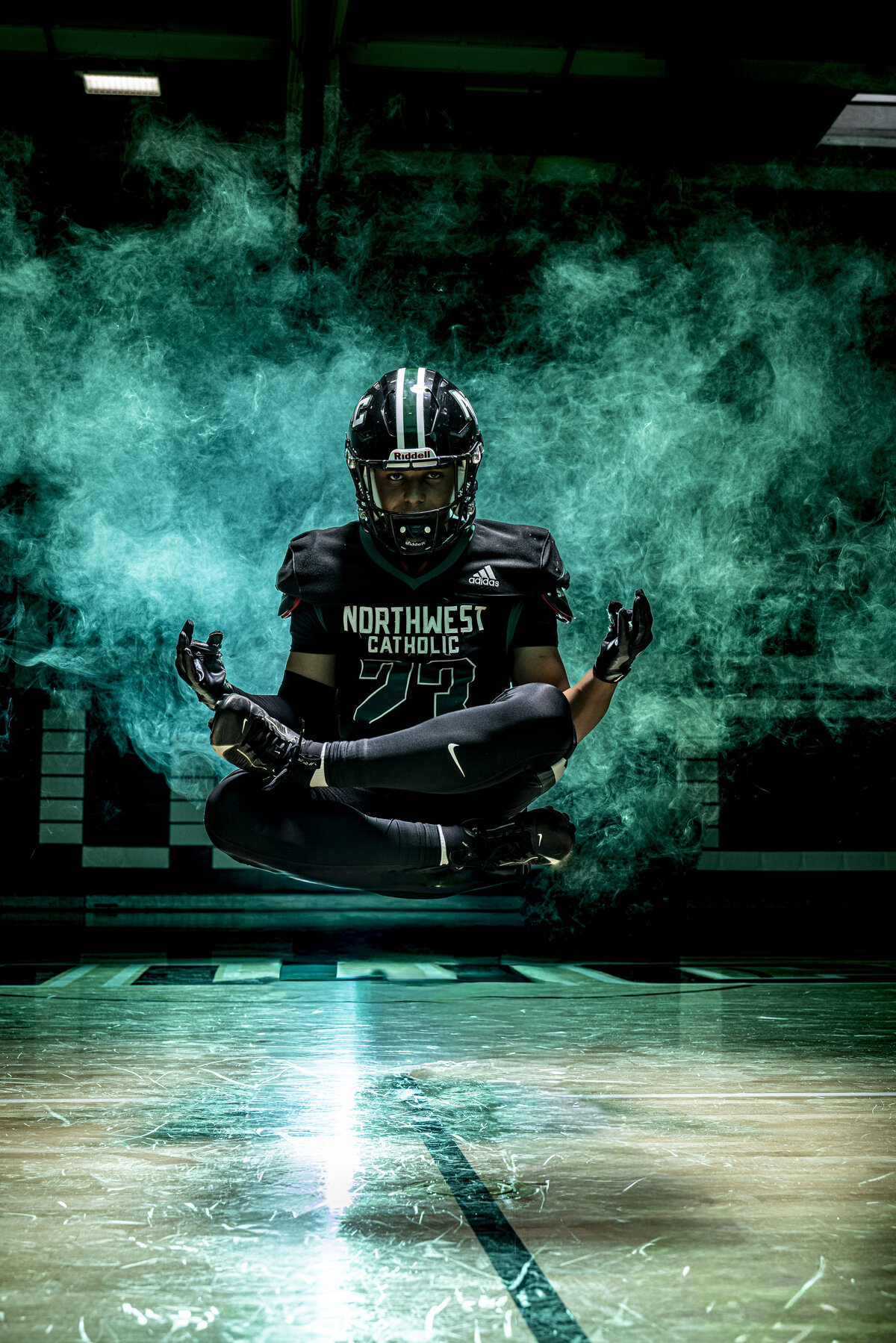 CT Photographer | Media Day Photos | Football Player Photos - Football player sitting in mid air levitating with green smoke behind him.