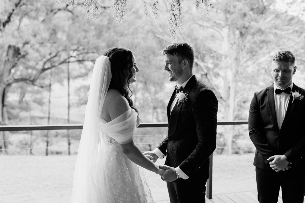 A tender moment captured: a couple, hands entwined, immersed in the solemn beauty of their ceremony.